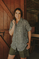 Woman standing in front of a wooden door wearing a striped shirt and shorts.